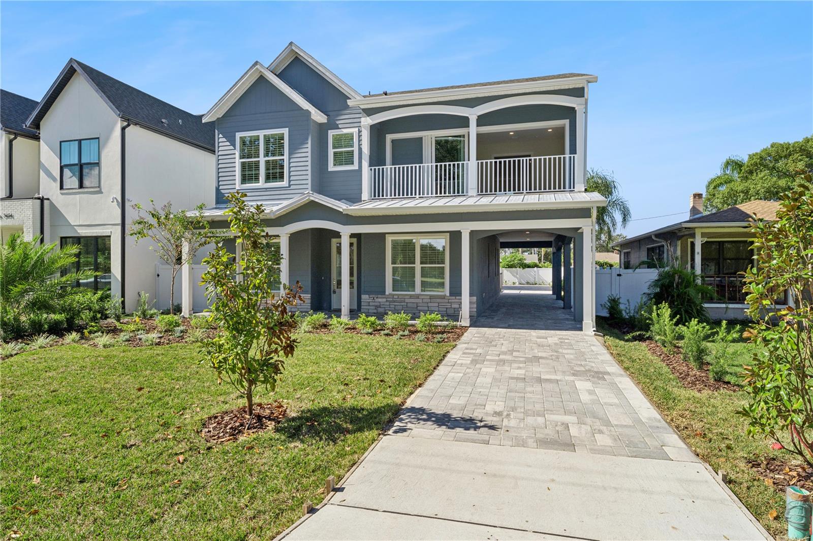 A driveway-side view shows the home's front porch, balcony, and covered side passage.