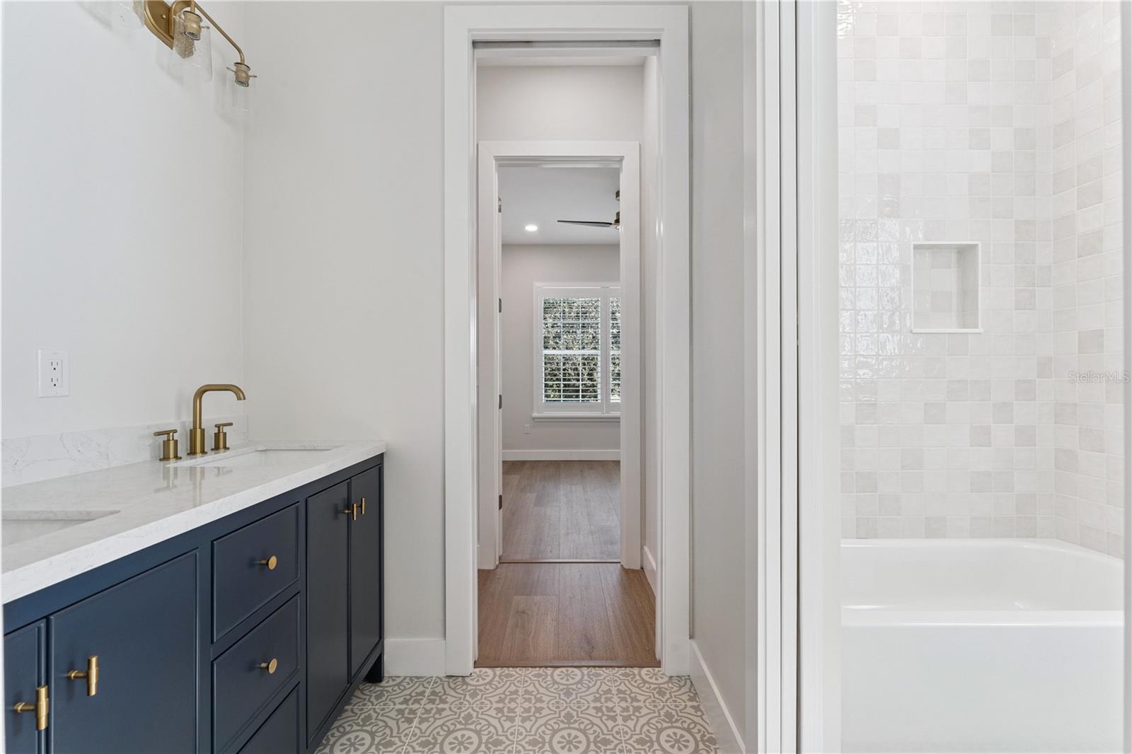 A navy double vanity pairs with patterned flooring and a tub-and-shower combination.