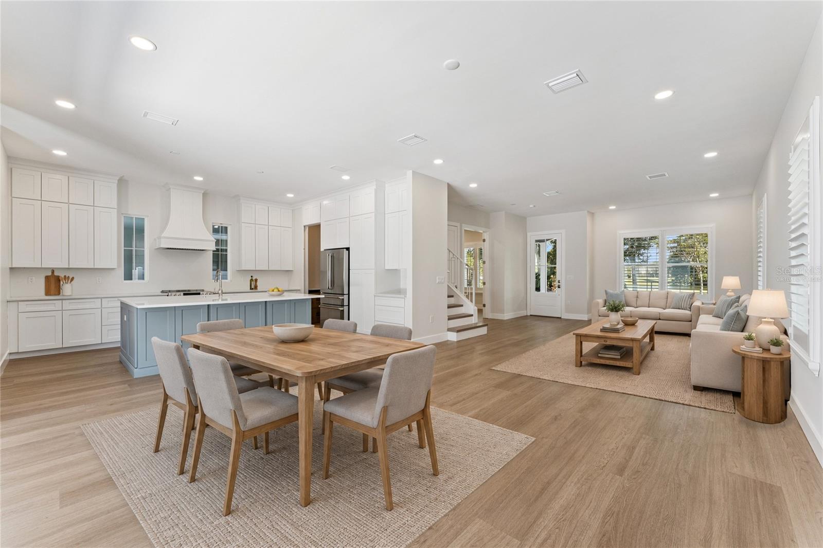Virtually Staged - An open living area connects to the kitchen, with a blue island and coordinated white cabinetry.