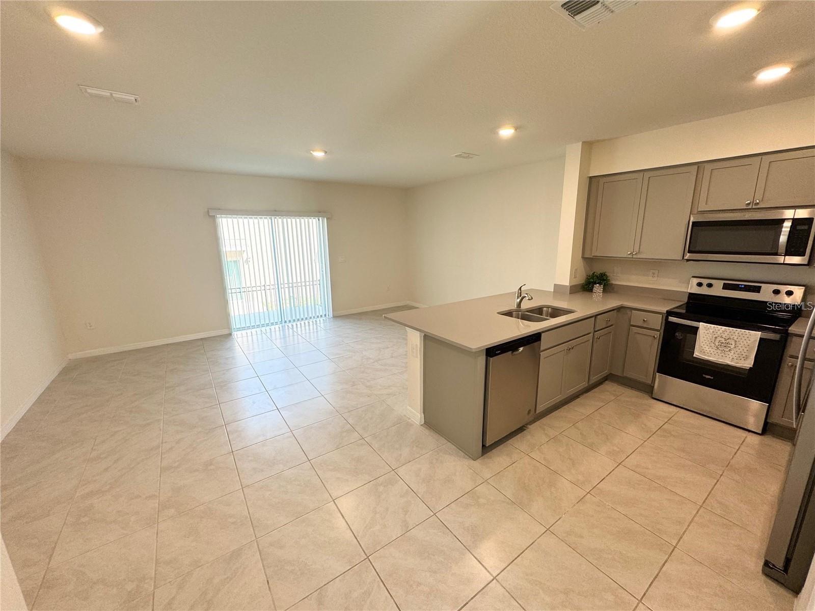 View of living room, sliding doors, dining area and kitchen.