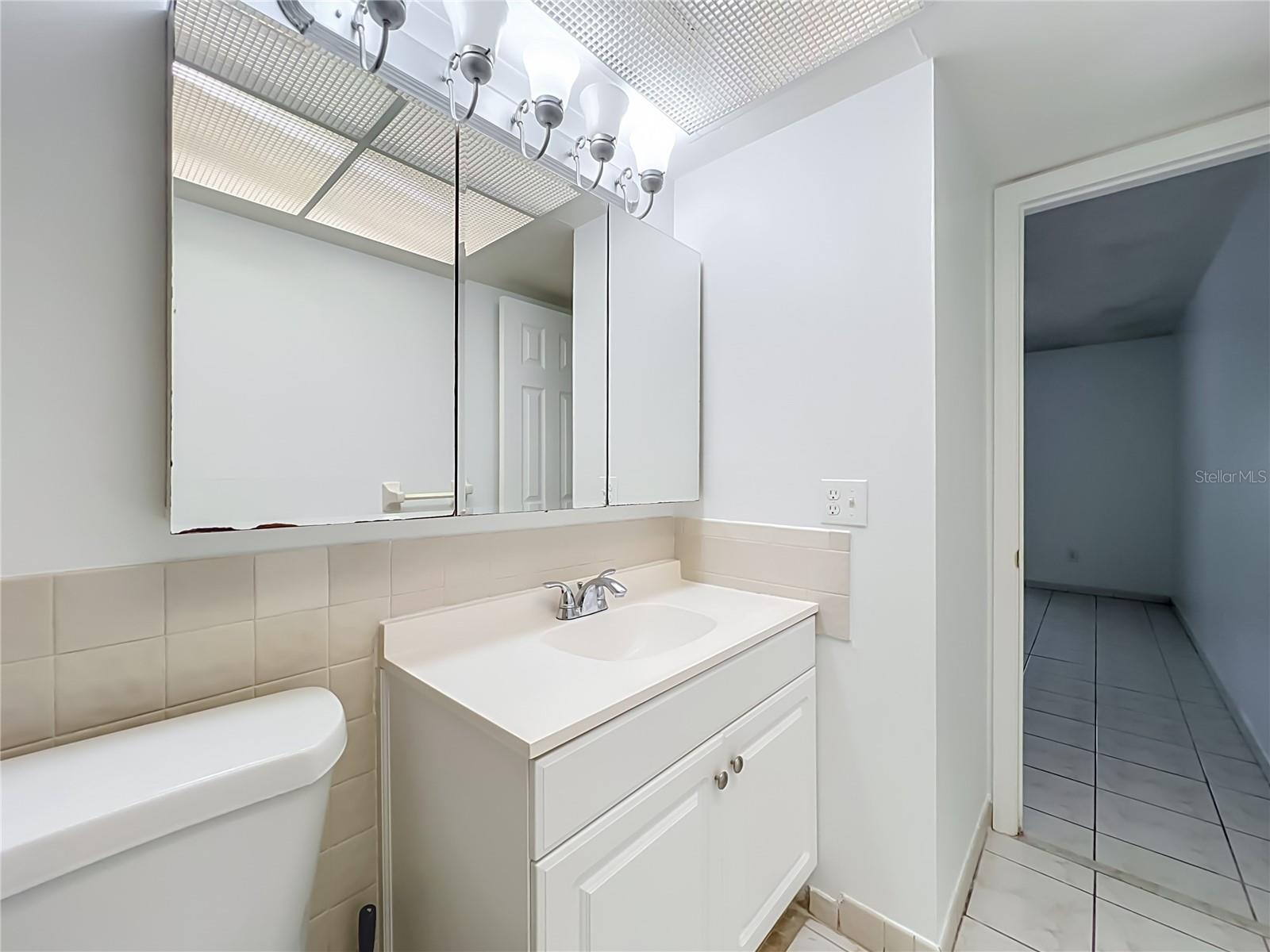 Bright vanity area with mirrored medicine cabinet and additional storage.