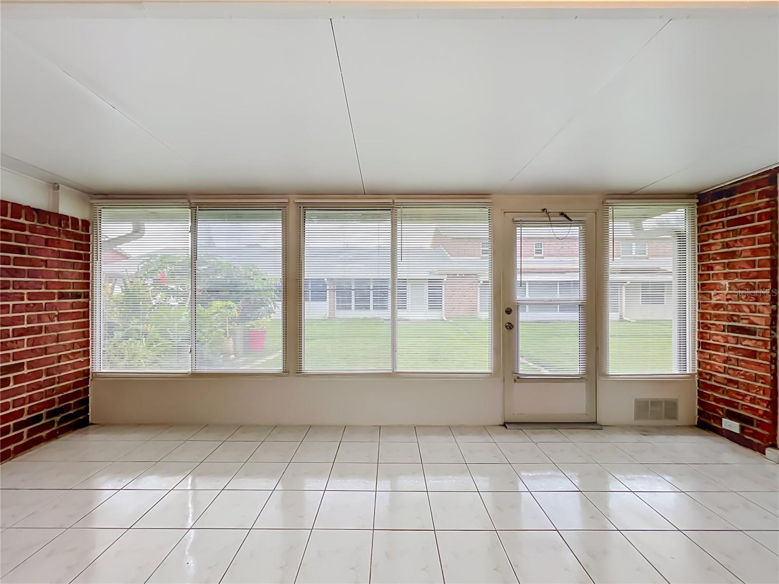 Spacious enclosed Florida room with tile flooring and wall-to-wall windows.