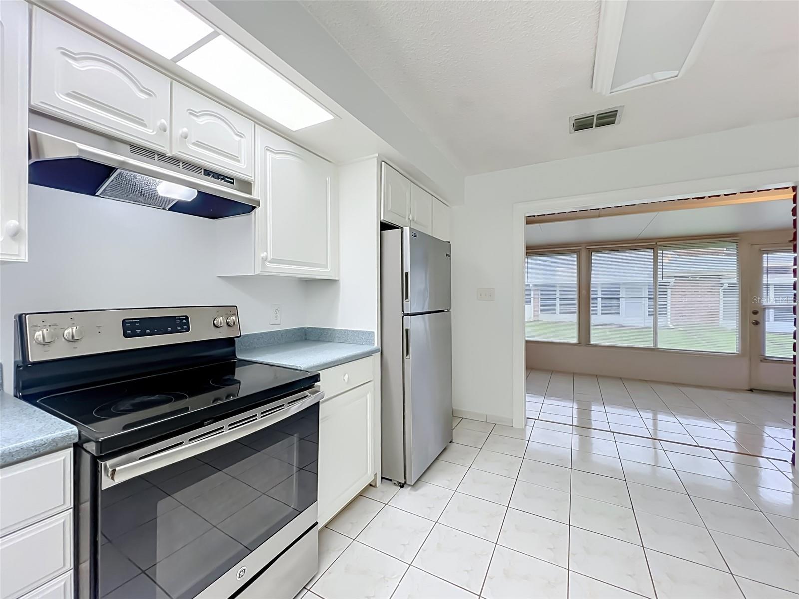 Bright kitchen with white cabinetry, ample storage and included appliances.