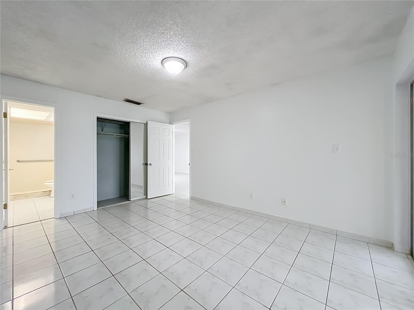 Spacious primary bedroom with ceramic tile flooring and plenty of room to make it your own.