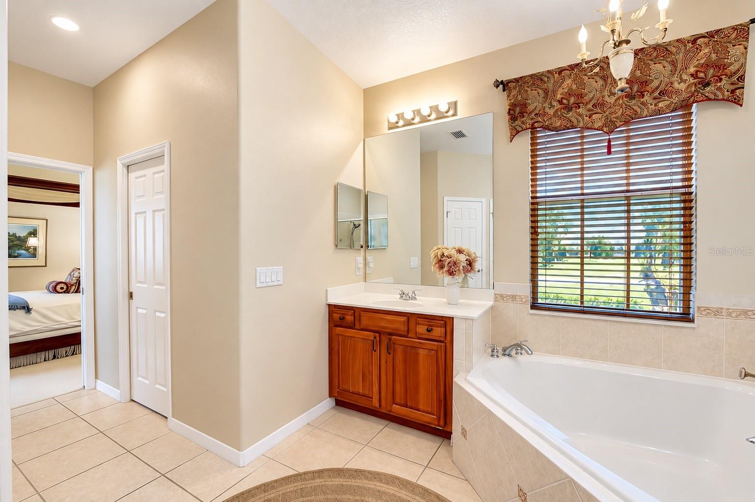 DUAL VANITIES WITH RICH WOOD CABINETRY, A LARGE SOAKING GARDEN TUB, AND A SEPARATE WALK-IN SHOWER WITH CUSTOM TILEWORK AND GLASS ENCLOSURE!