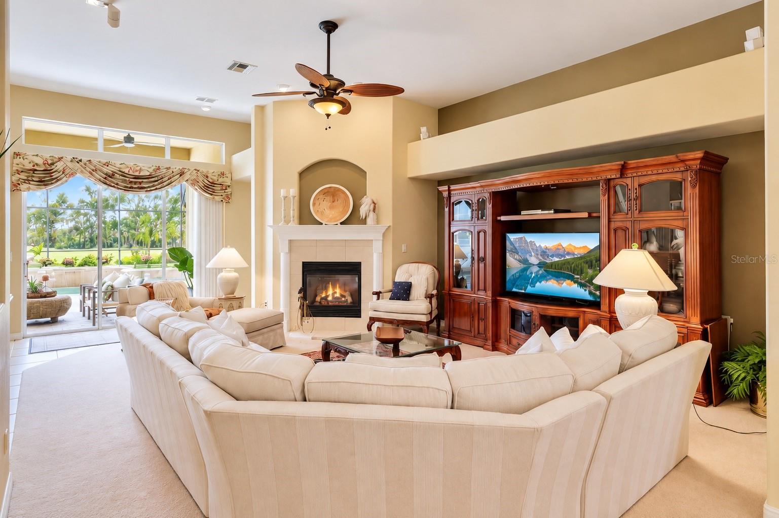 STUNNING, SPACIOUS FAMILY ROOM FEATURING SOARING CEILINGS, A BEAUTIFUL GAS FIREPLACE, ELEGANT ARCHITECTURAL DETAILS, AND ABUNDANT NATURAL LIGHT! Expansive sliding glass doors provide picturesque views of the sparkling pool and lush tropical landscaping while creating a seamless flow to the covered lanai. The perfect gathering space for cozy evenings by the fireplace, entertaining guests, and enjoying Florida's indoor-outdoor lifestyle! STUNNING, SPACIOUS FAMILY ROOM FEATURING SOARING CEILINGS, A BEAUTIFUL GAS FIREPLACE, ELEGANT ARCHITECTURAL DETAILS, AND ABUNDANT NATURAL LIGHT! Expansive sliding glass doors provide picturesque views of the sparkling pool and lush tropical landscaping while creating a seamless flow to the covered lanai. The perfect gathering space for cozy evenings by the fireplace, entertaining guests, and enjoying Florida's indoor-outdoor lifestyle!