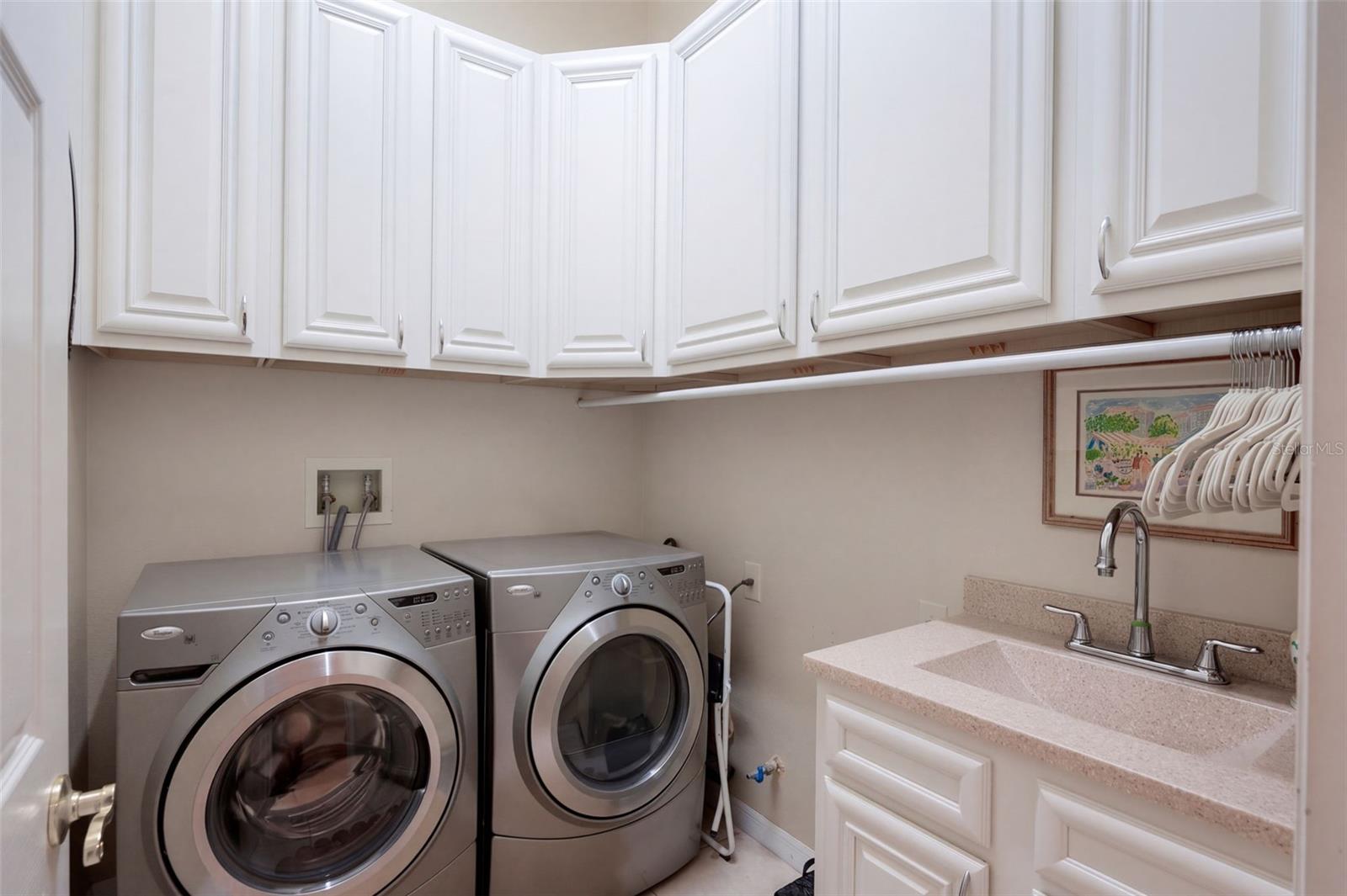 CUSTOM LAUNDRY ROOM FEATURING BEAUTIFUL CABINETRY, AMPLE STORAGE SPACE, AND A CONVENIENT UTILITY SINK FOR ADDED FUNCTIONALITY!