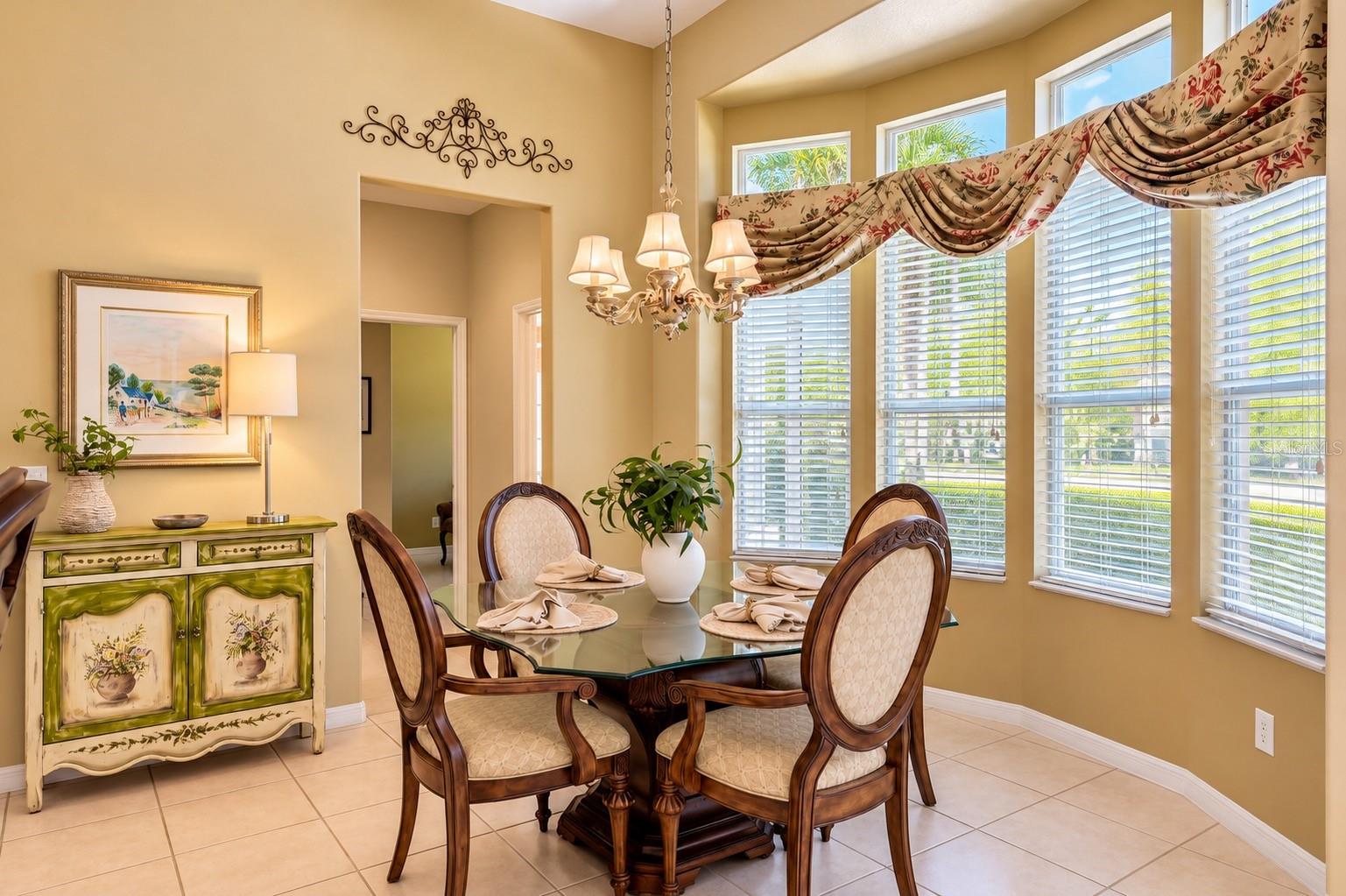 CHARMING BREAKFAST NOOK FEATURING SOARING CEILINGS, ELEGANT LIGHTING, AND A BEAUTIFUL CURVED WALL OF WINDOWS THAT FILLS THE SPACE WITH NATURAL LIGHT! Enjoy peaceful mornings with your favorite cup of coffee while overlooking the lush outdoor landscaping. The perfect setting for casual dining and everyday gatherings! CHARMING BREAKFAST NOOK FEATURING SOARING CEILINGS, ELEGANT LIGHTING, AND A BEAUTIFUL CURVED WALL OF WINDOWS THAT FILLS THE SPACE WITH NATURAL LIGHT! Enjoy peaceful mornings with your favorite cup of coffee while overlooking the lush outdoor landscaping. The perfect setting for casual dining and everyday gatherings!