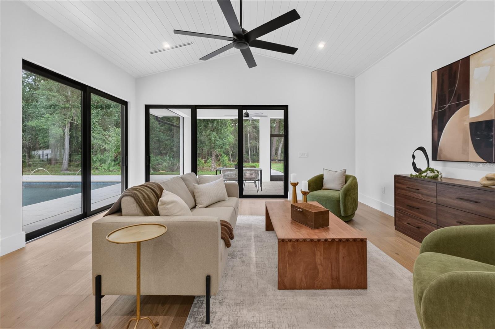 Game room features a wet bar with beverage refrigerator and two large sliding glass doors that provide direct access to pool and covered lanai