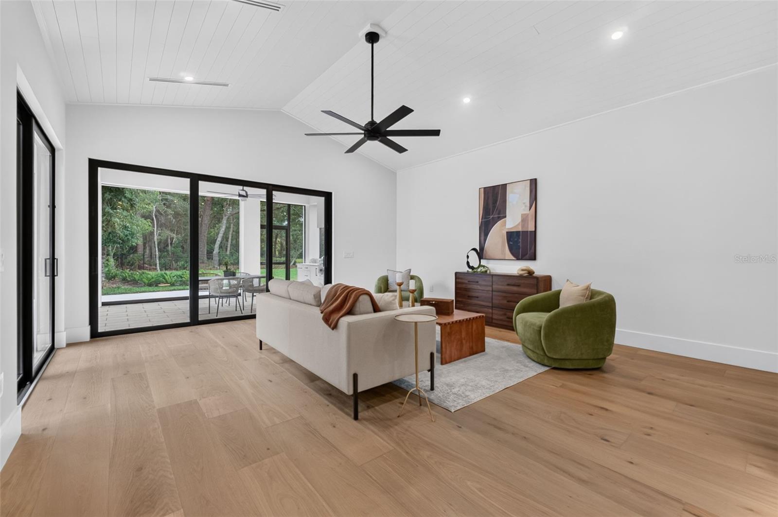 Game room features a wet bar with beverage refrigerator and two large sliding glass doors that provide direct access to pool and covered lanai