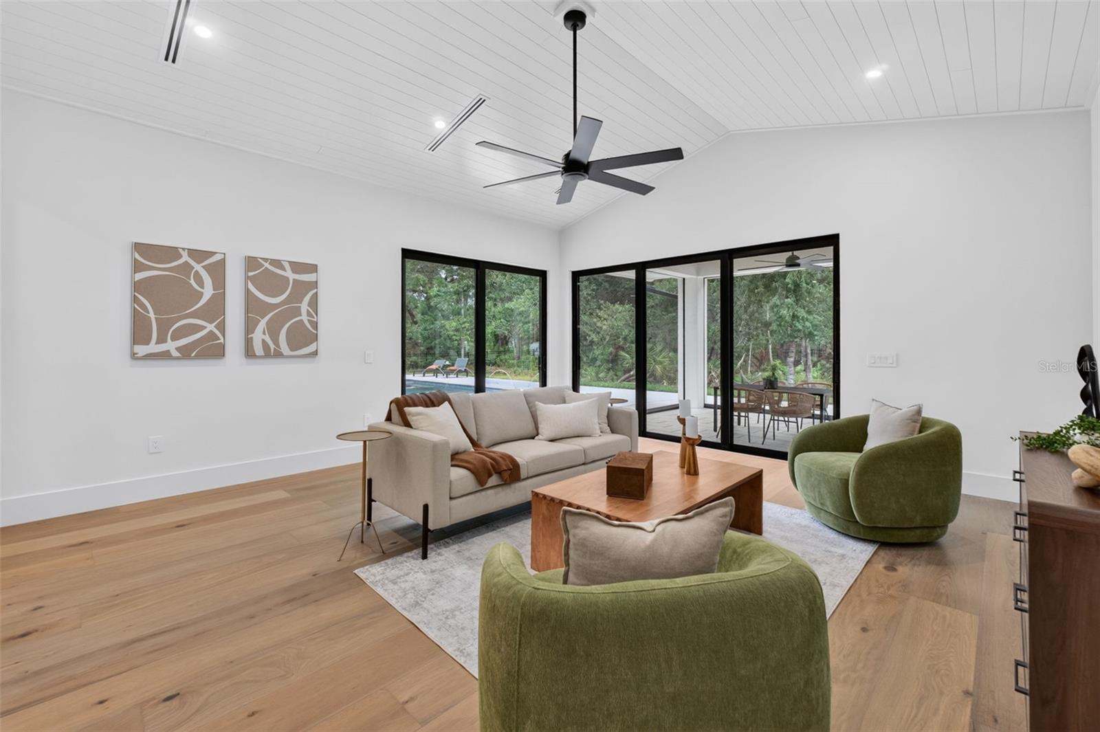 Game room features a wet bar with beverage refrigerator and two large sliding glass doors that provide direct access to pool and covered lanai