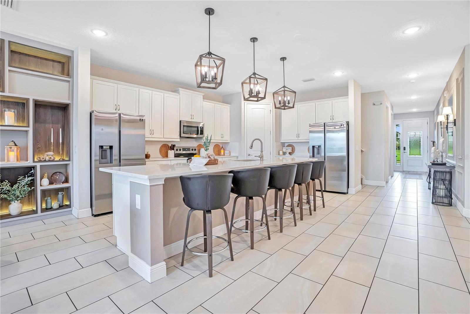 An impressive open-concept kitchen featuring an oversized island, elegant cabinetry, designer pendant lighting, and generous seating for gathering and entertaining