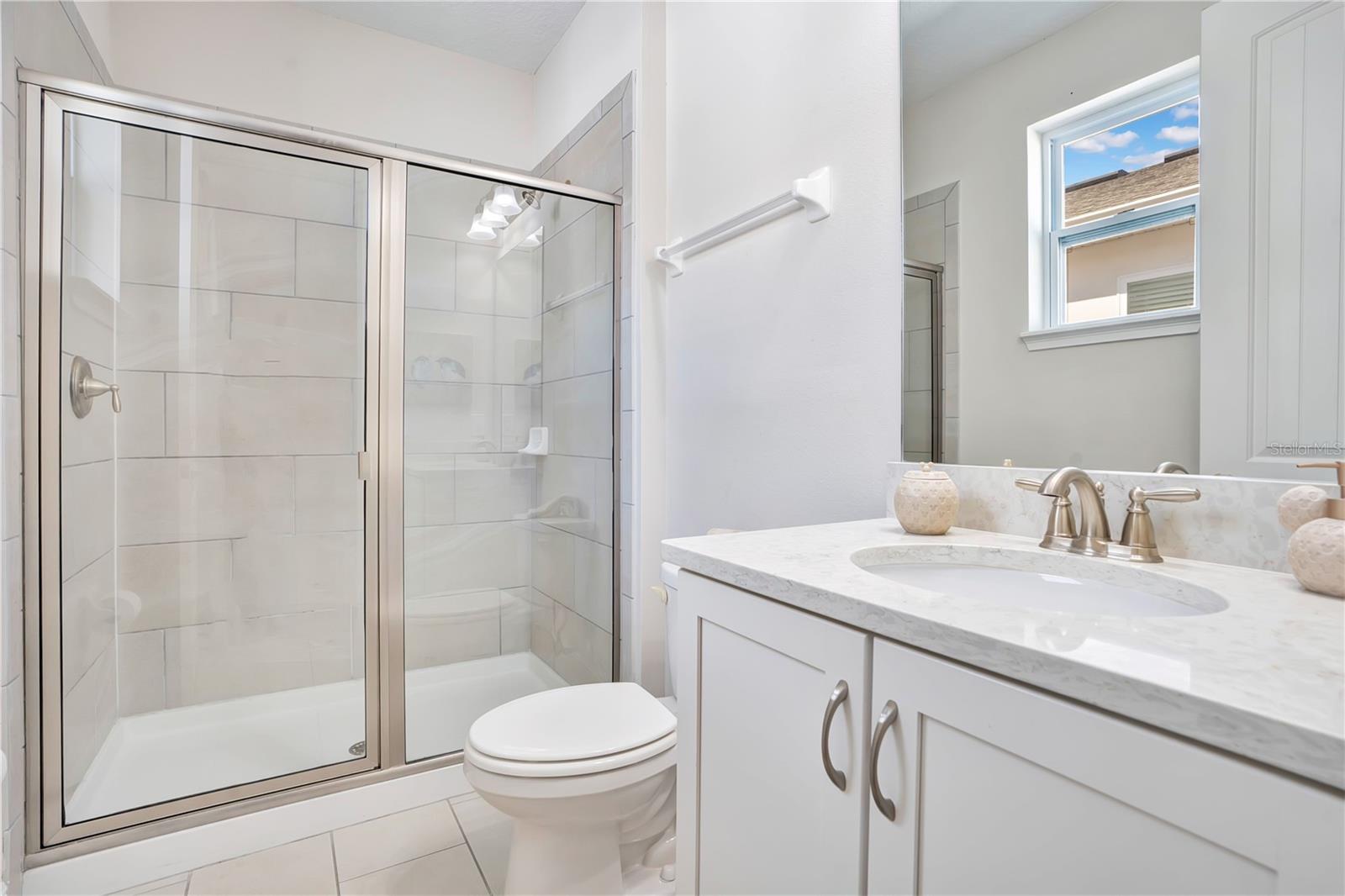A private en-suite bath with contemporary fixtures and a glass-enclosed shower