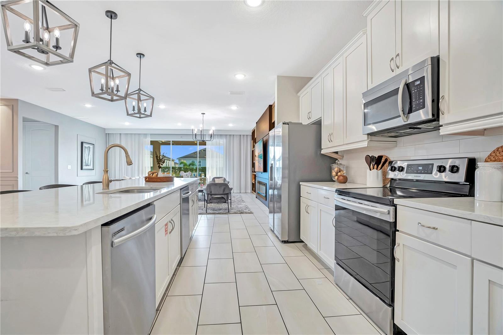 A beautifully equipped kitchen combines abundant cabinetry, stainless steel appliances, generous preparation space, and an inviting open layout