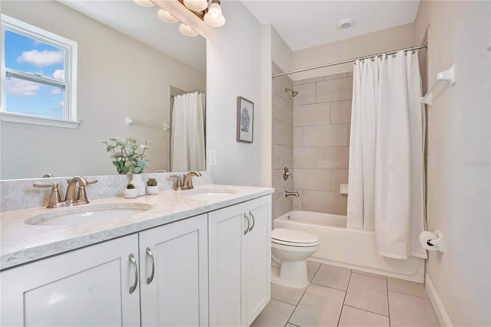 A beautifully finished en-suite bathroom with a spacious vanity and tub-shower combination