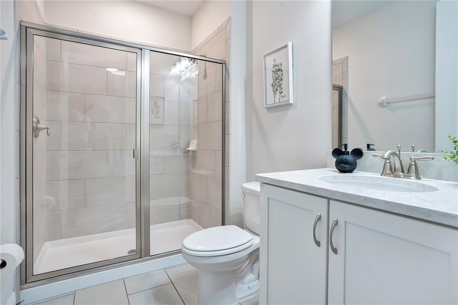 Private en-suite bath to Mickey & Minnie's Hideaway - with glass-enclosed shower and contemporary finishes