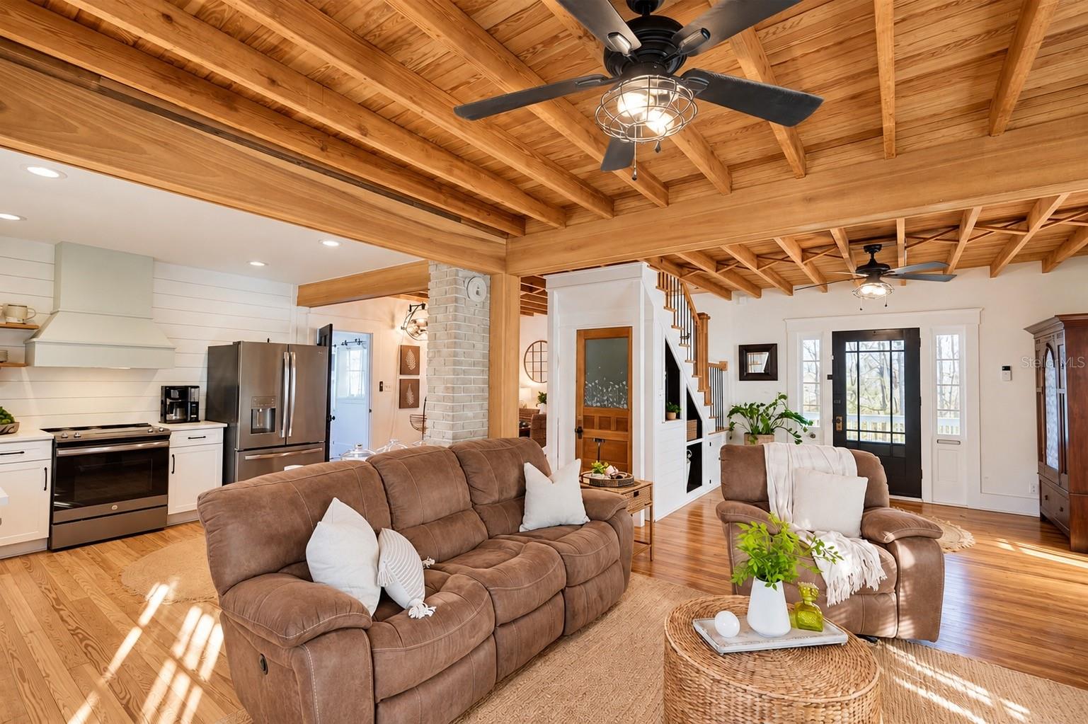 Beautiful OPEN-CONCEPT living area featuring stunning EXPOSED WOOD BEAM CEILINGS, gorgeous wood flooring, charming shiplap accents, and a seamless flow into the kitchen. Beautiful OPEN-CONCEPT living area featuring stunning EXPOSED WOOD BEAM CEILINGS, gorgeous wood flooring, charming shiplap accents, and a seamless flow into the kitchen.