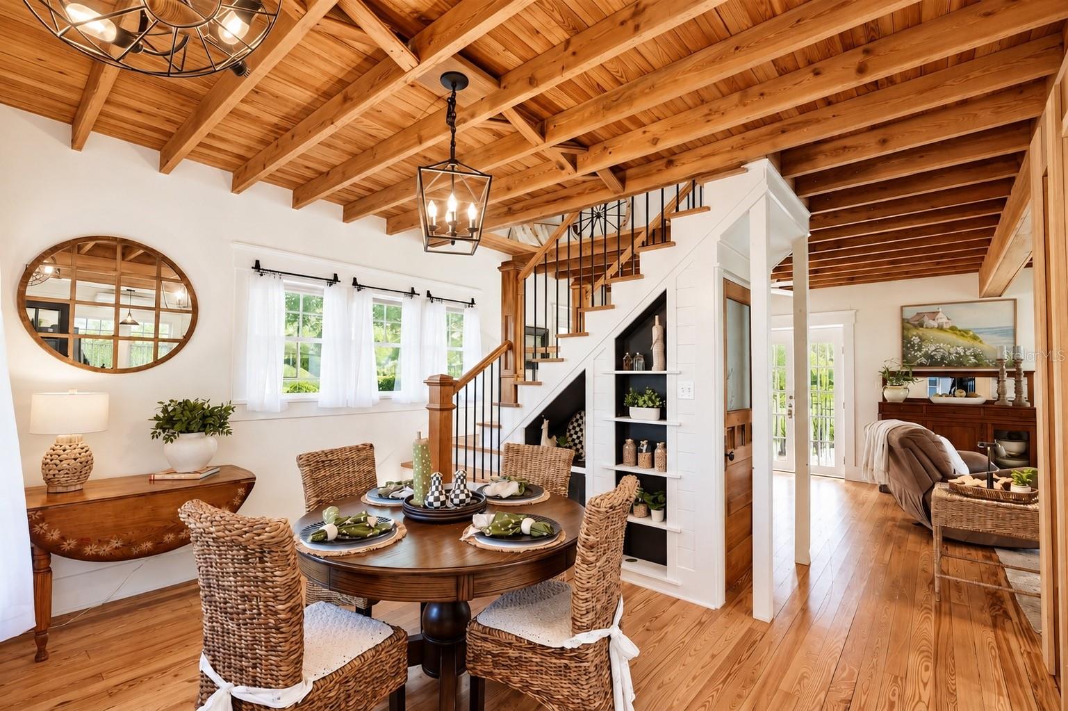 DINING AREA featuring stunning EXPOSED WOOD BEAM CEILINGS, beautiful WOOD FLOORING, stylish pendant lighting, and CUSTOM BUILT-IN SHELVING beneath the staircase. DINING AREA featuring stunning EXPOSED WOOD BEAM CEILINGS, beautiful WOOD FLOORING, stylish pendant lighting, and CUSTOM BUILT-IN SHELVING beneath the staircase.