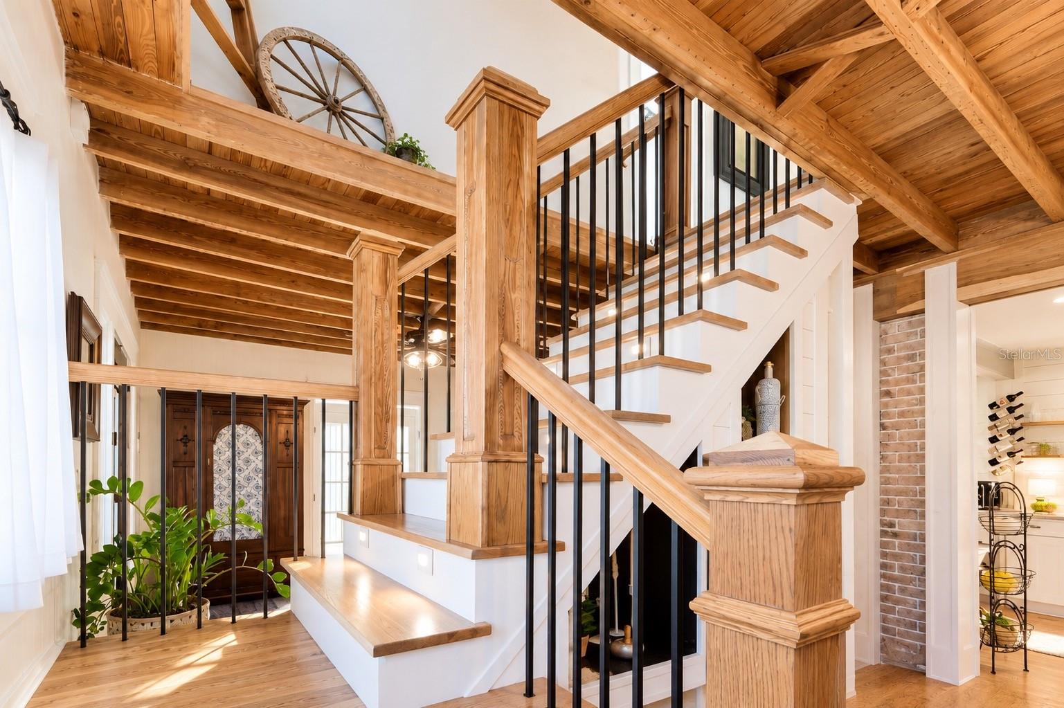 Beautiful custom wood staircase featuring rich wood posts and handrails, contrasting black iron balusters, and exposed wood beam ceilings that add warmth and architectural character throughout the home.