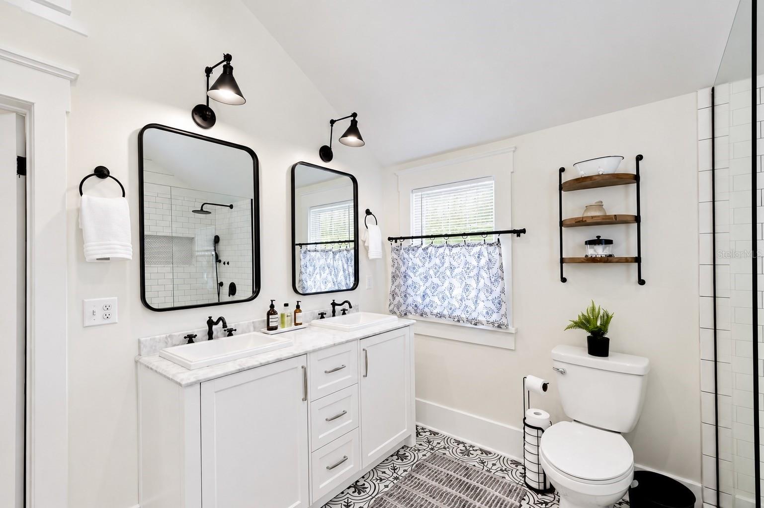 Beautifully updated upstairs bathroom featuring a spacious DOUBLE-SINK VANITY with marble-look countertops, stylish black fixtures, individual mirrors and lighting, ample cabinet storage, and gorgeous patterned tile flooring. Conveniently located between both upstairs bedrooms.