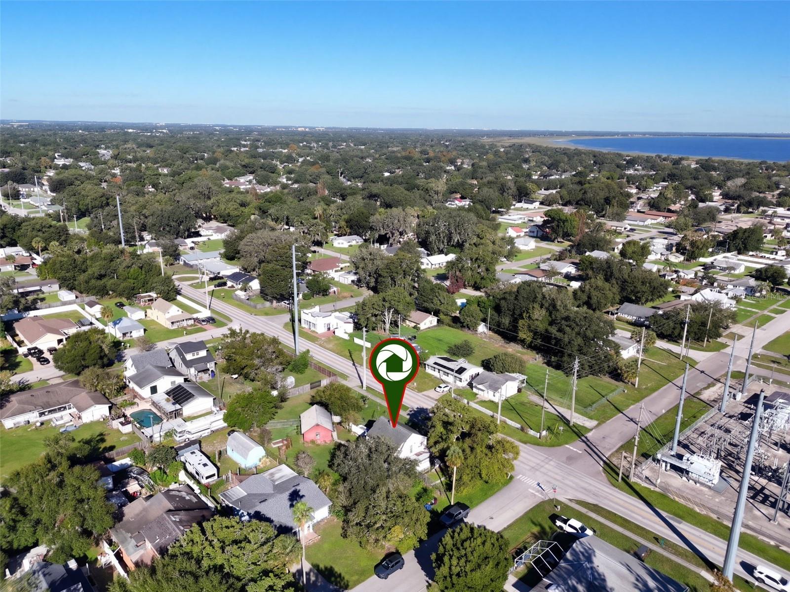 Aerial view showcasing this charming farmhouse situated on an expansive .34-ACRE CORNER LOT with a FENCED BACKYARD, BARN WITH ELECTRICITY, and an abundance of edible fruit trees, plants, and herbs. Enjoy the beauty of a well-established neighborhood with mature trees and the added bonus of a nearby lake!