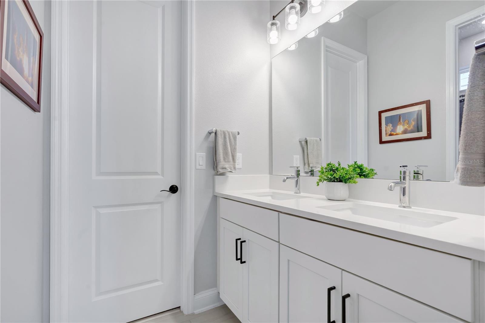 Full guest bath with quartz vanity, framed mirror, and modern fixtures.