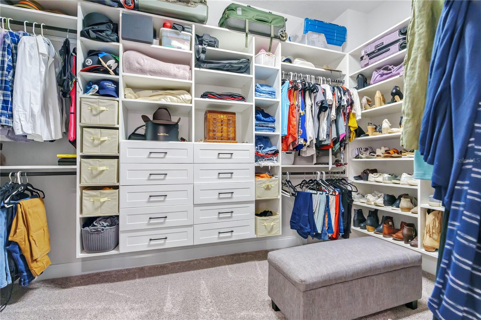 Oversized primary walk in closet with custom built ins, shelving, and drawers for organized storage.