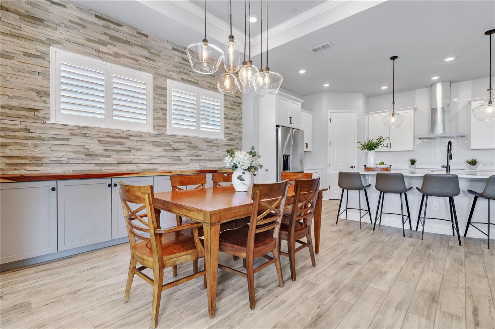 Dining area with a stone accent wall and modern chandelier, steps from the kitchen. Ideal for dinners at home in Lake Nona.
