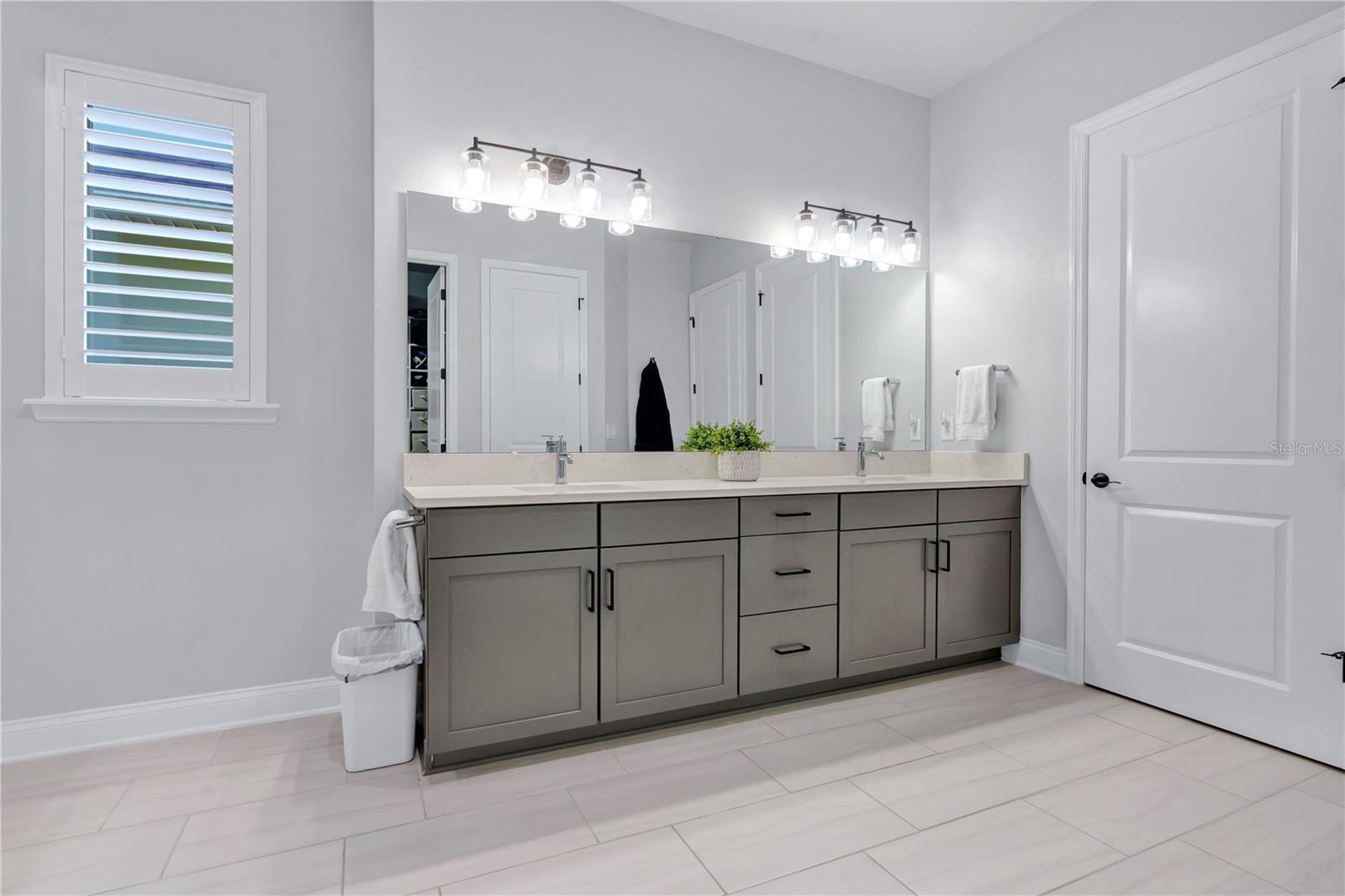 Primary bath vanity with dual sinks, quartz counters, framed mirrors, and modern lighting.