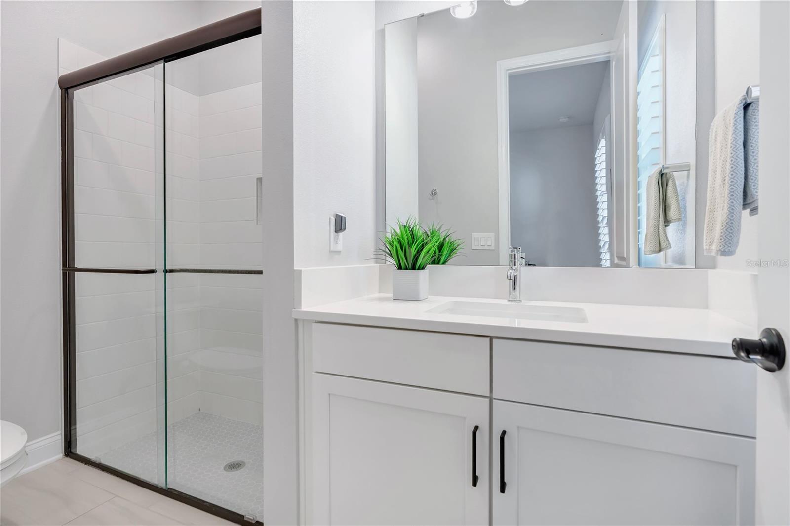 Secondary bath with walk in shower with tile to the ceiling, ceiling mounted rain shower head, and hex mosaic floor.