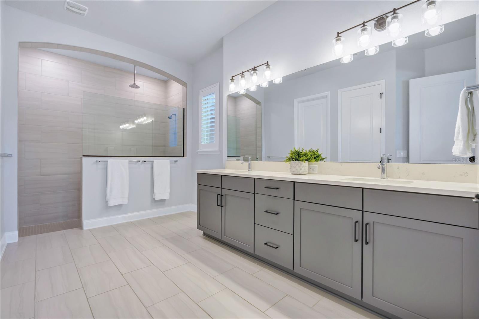 Primary bath with a Carrara Marmi quartz double vanity, extra drawer storage, and a large walk in shower.