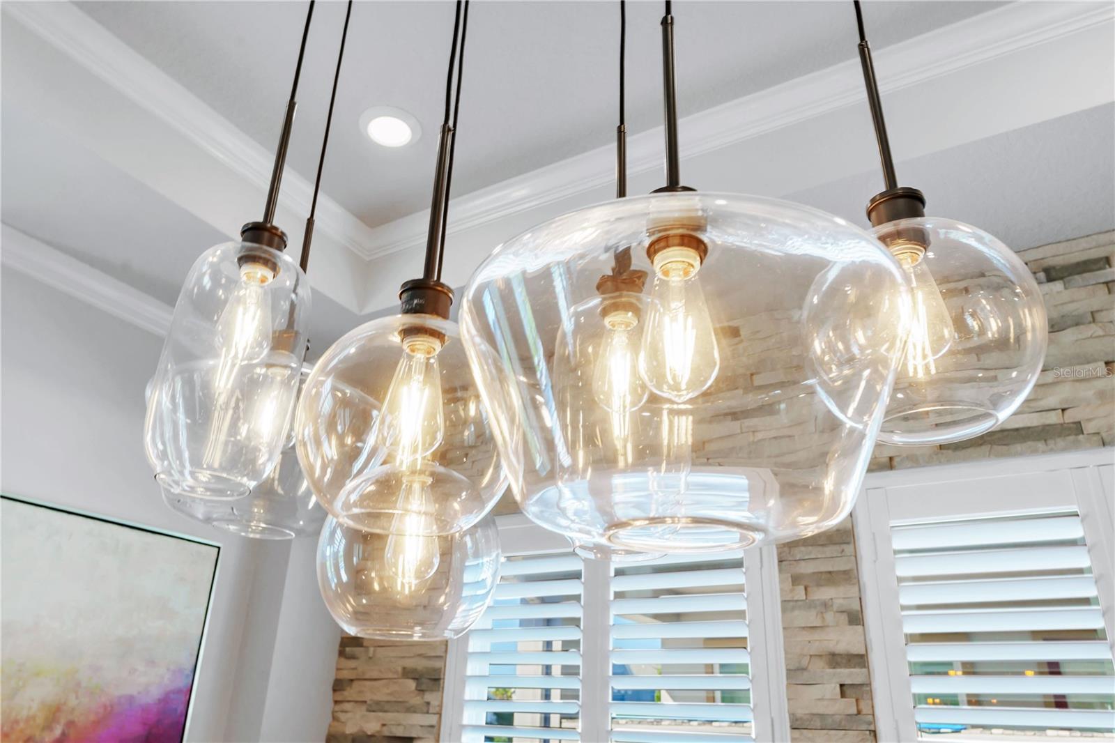 Designer glass pendant lights over the dining table add warmth and style.