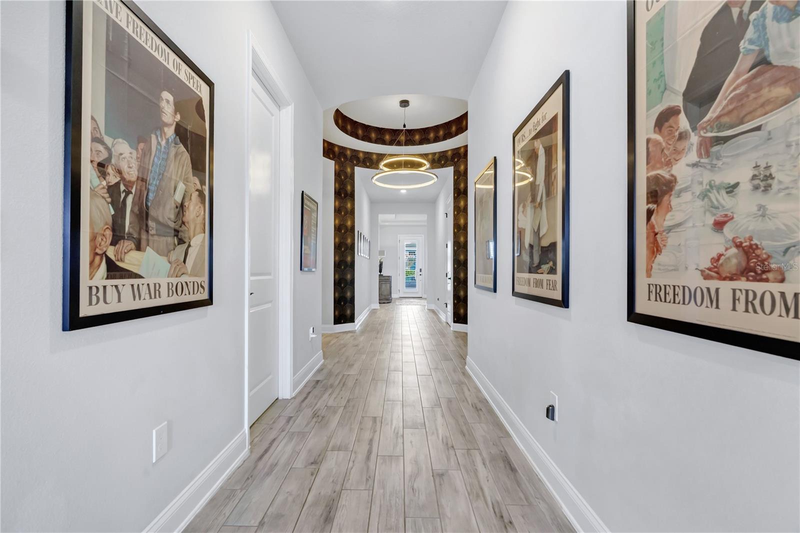 Gallery style entry hallway with wood look plank tile, wide baseboards, and crown moulding welcoming you inside.