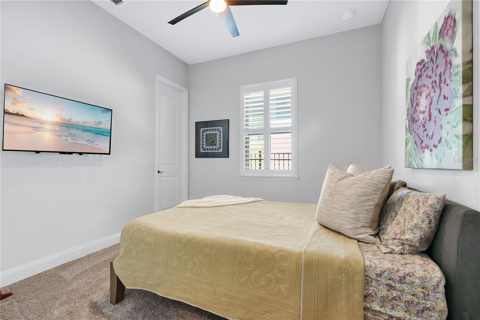 Secondary bedroom with ceiling fan, carpet, and natural light.