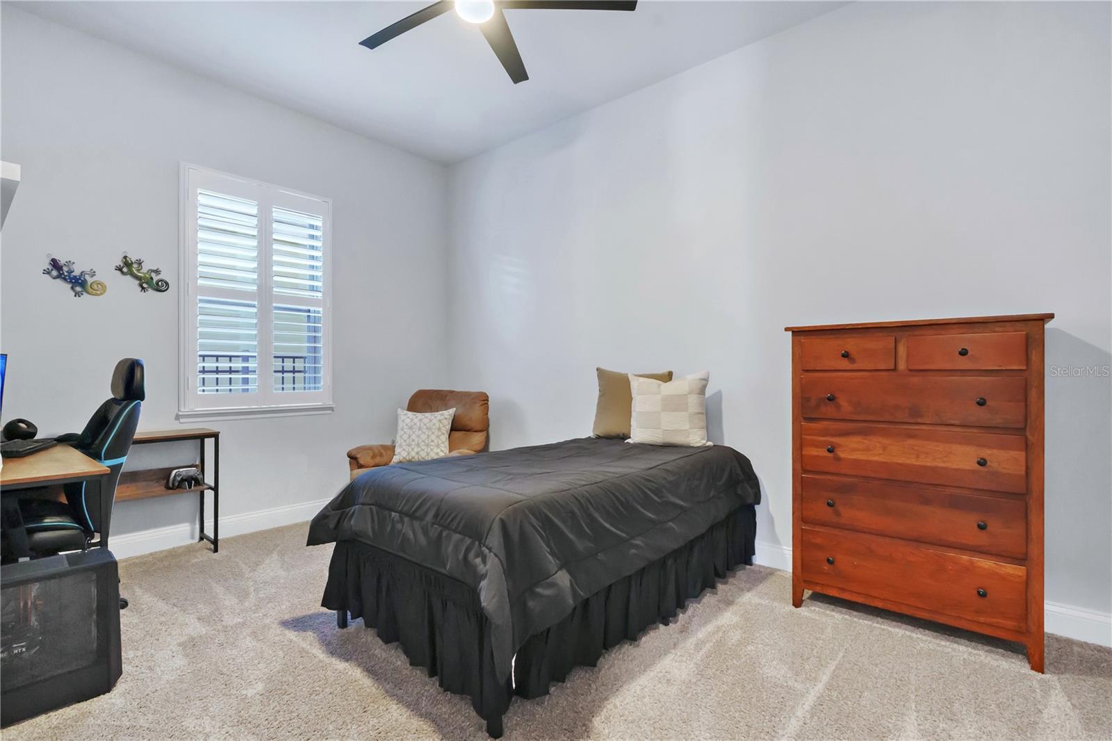 Secondary bedroom with ceiling fan, carpet, and a built in closet system.