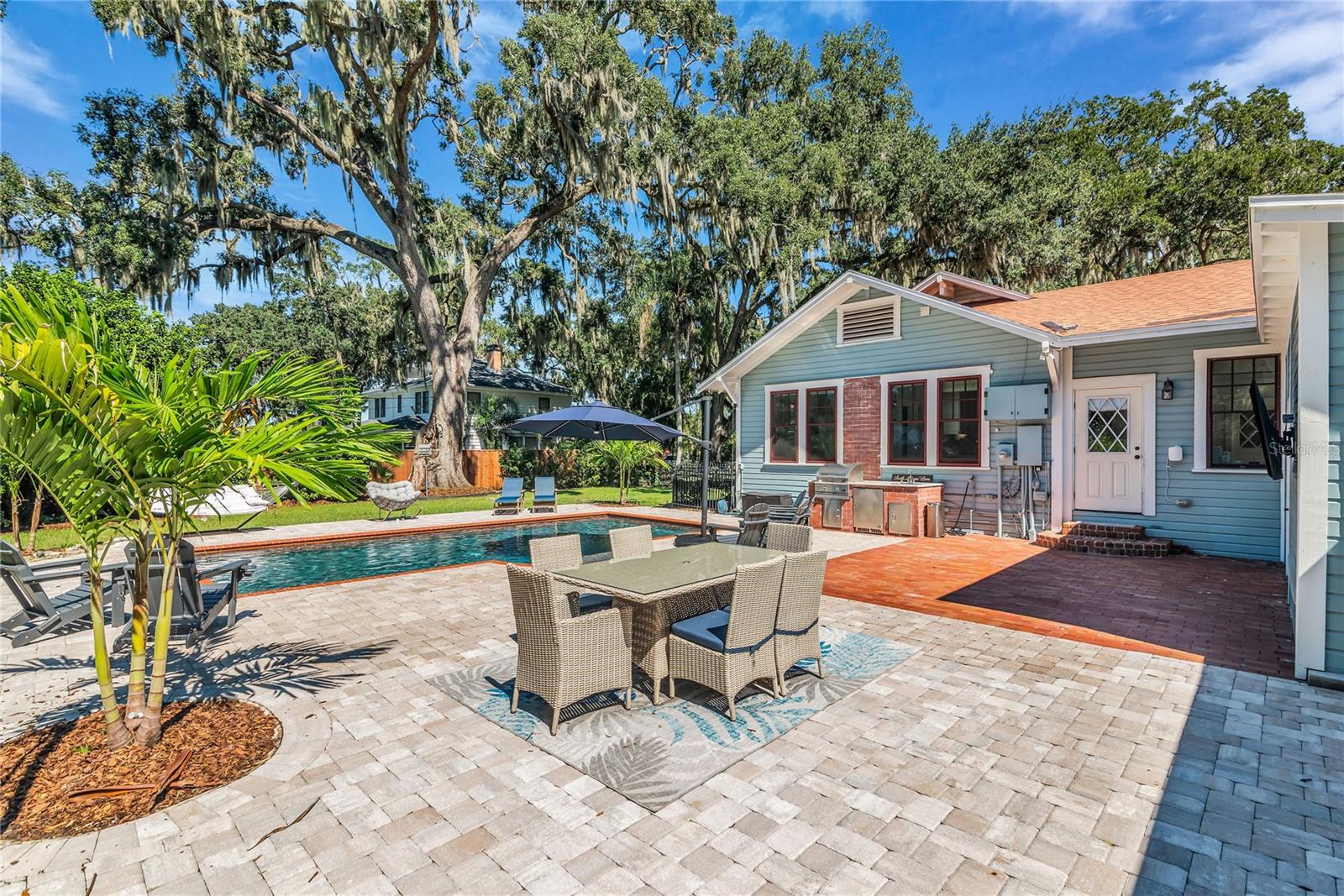 The enormous fully fenced backyard is designed for year-round enjoyment with a gas-heated saltwater sport pool, outdoor kitchen, expansive brick paved deck, detached covered lanai, and low-maintenance turf.