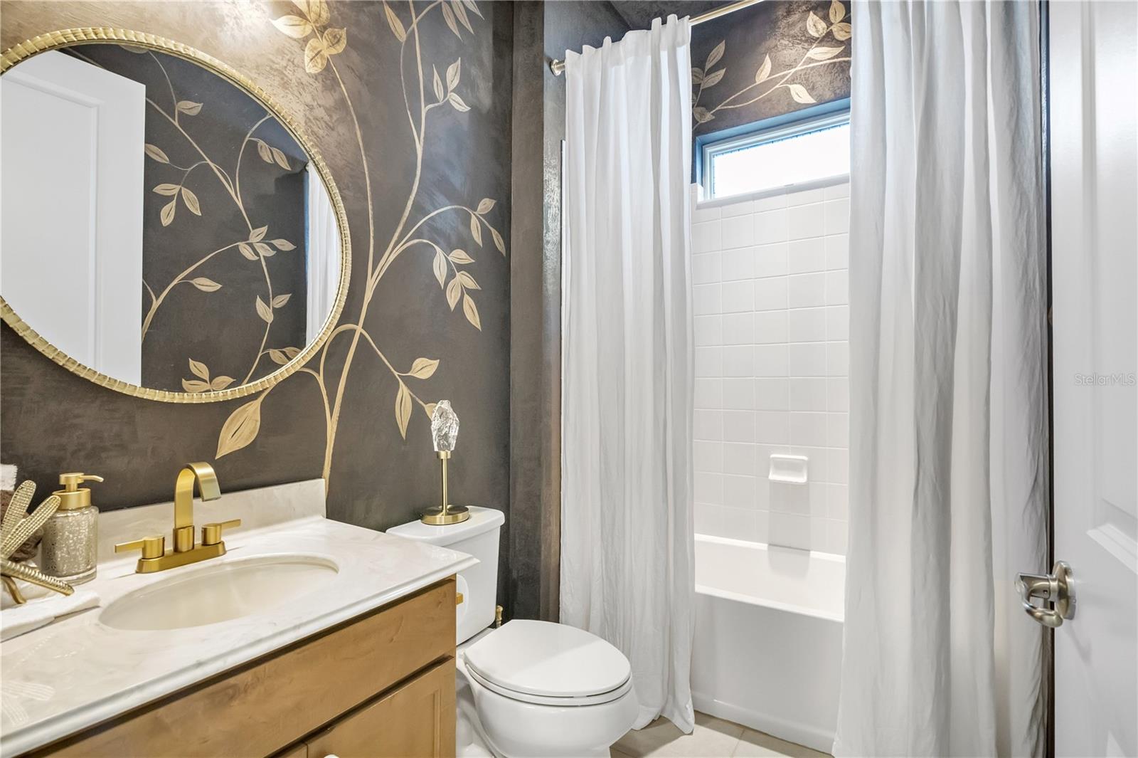 Beautifully styled bathroom featuring decorative wall finishes and elegant gold accents.