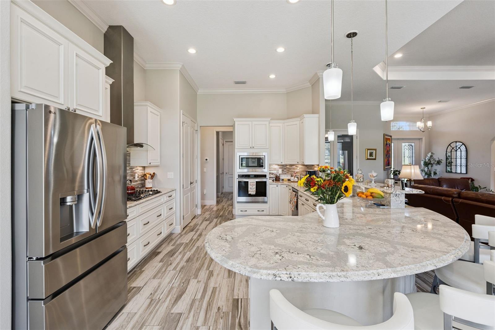 Designer kitchen featuring high-end stainless steel appliances, including a professional-grade gas cooktop, built-in wall oven, and a sleek modern vent hood.
