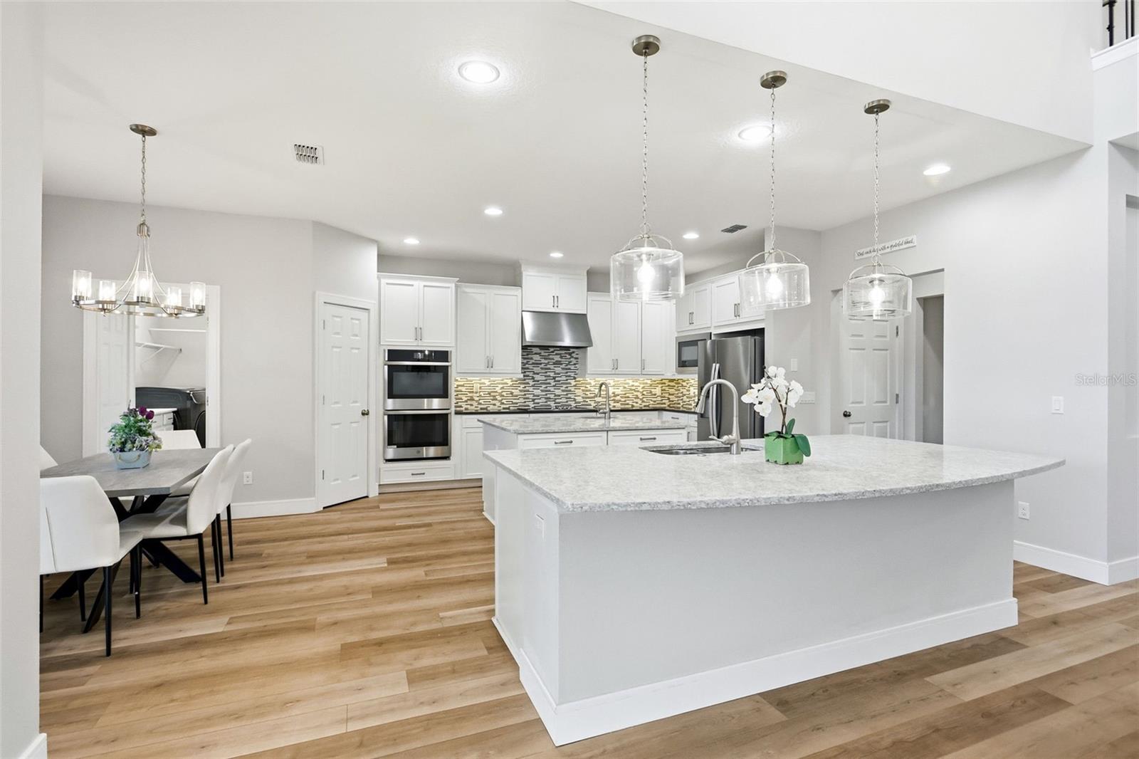 Stunning kitchen featuring built in double ovens, walk-in pantry and beautiful lighting