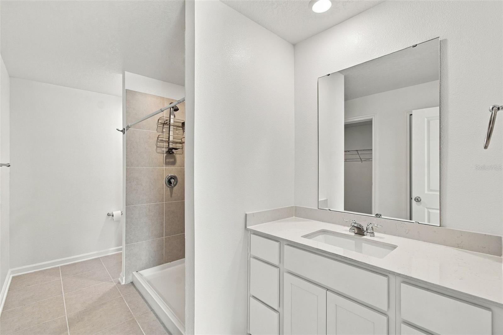 The private owners suite is tucked away at the back of the home and features an en-suite bathroom with dual sinks, a walk-in shower, and a generous walk-in closet.