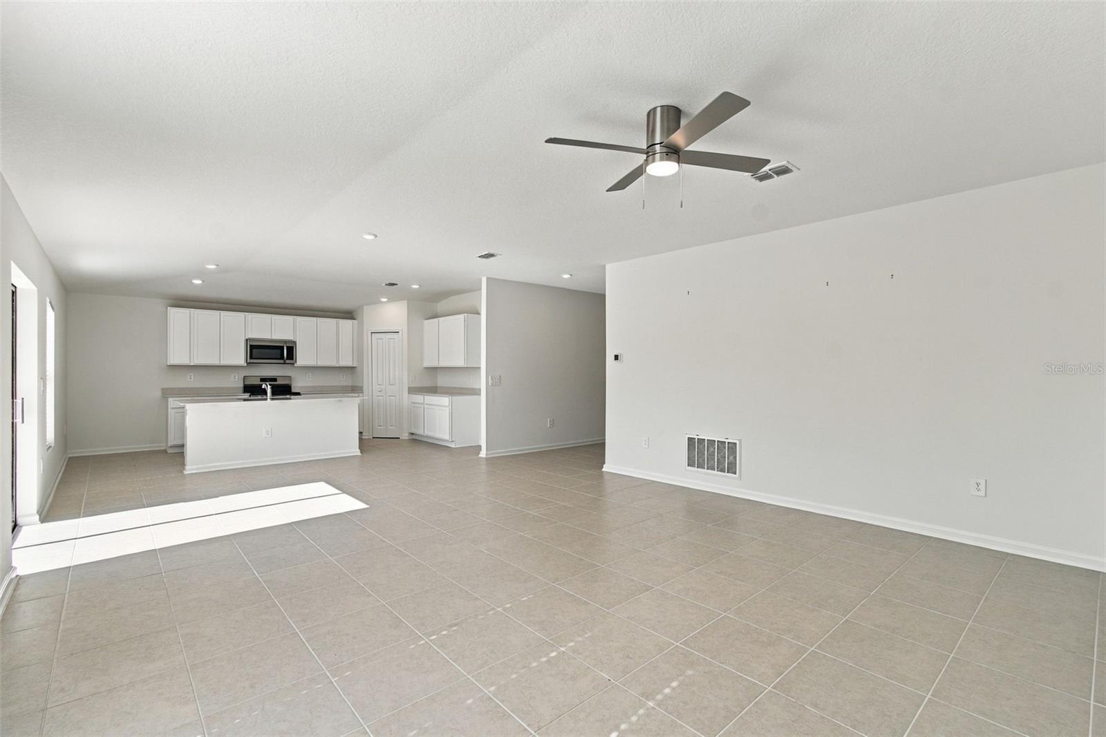 The kitchen offers a spacious island with breakfast bar, white Shaker-style cabinetry, and quartz countertops, all overlooking the dining and living areas.