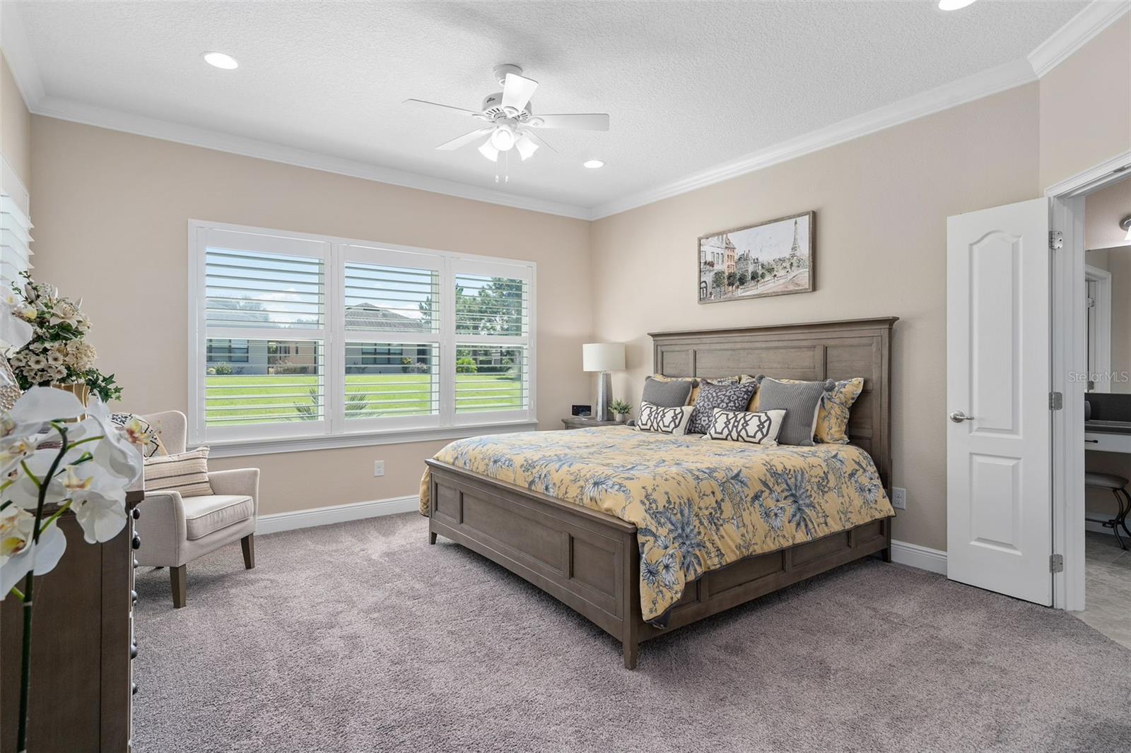 Primary Bedroom is spacious offering great natural light, Plantation Shutters, additional ceiling lighting plus a fan, Crown Molding, Walk-in Custom Organized Closet and a great En-Suite.