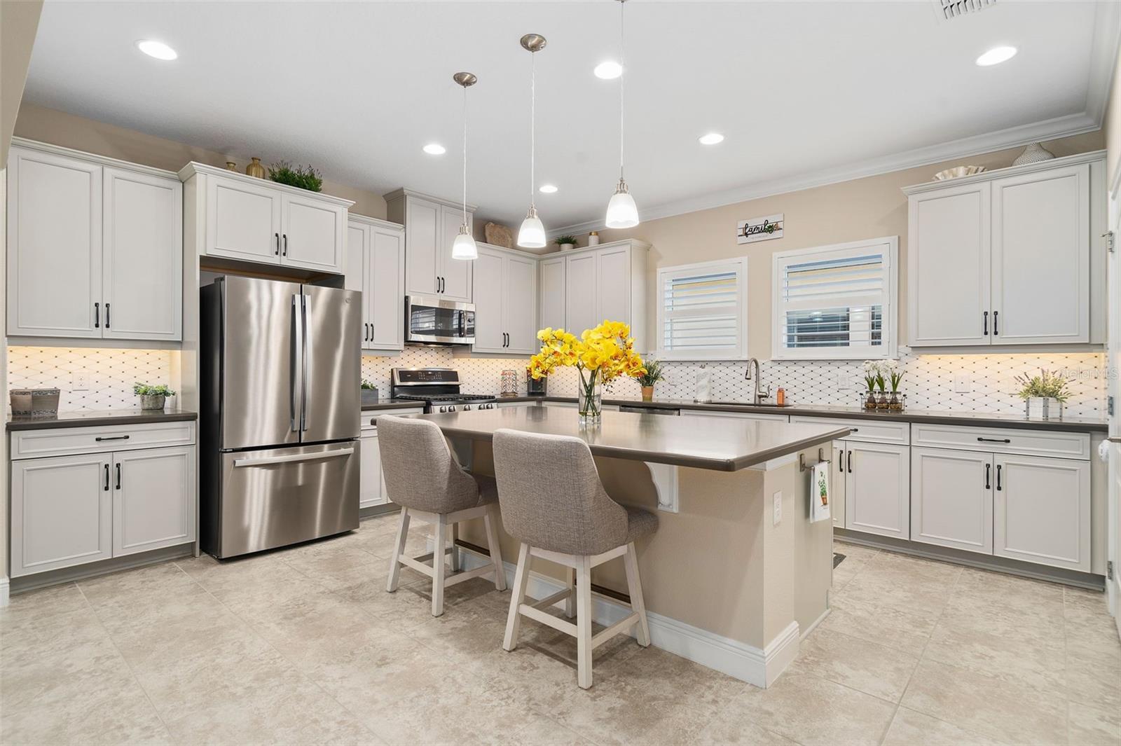 What a Beautiful Kitchen with a Natural Stone Backsplash, Pendant Lighting, Quartz Countertops, Upgraded Stainless Steel Appliances and Plantation Shutters.