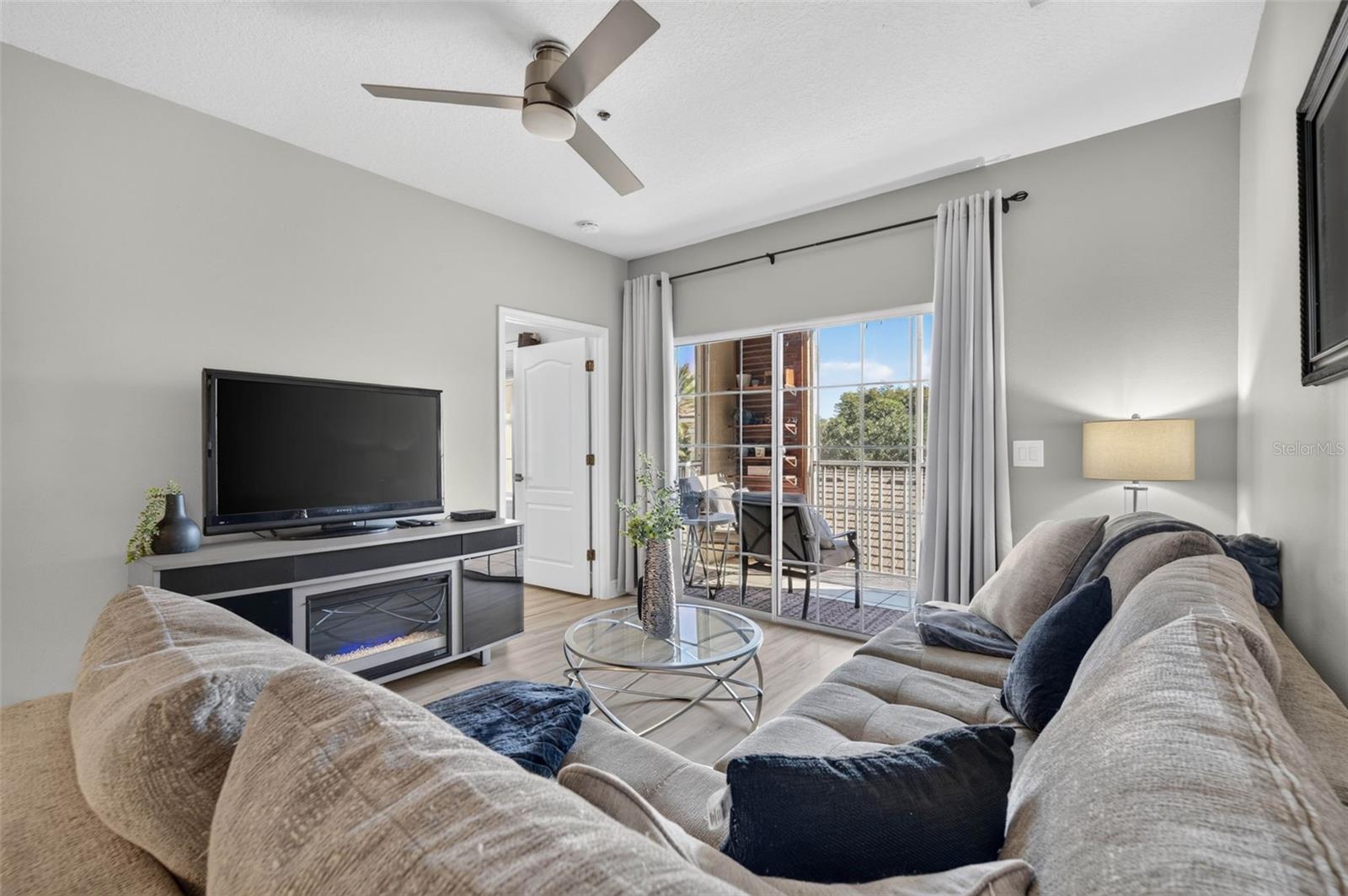 Living room with TV, ceiling fan and balcony door