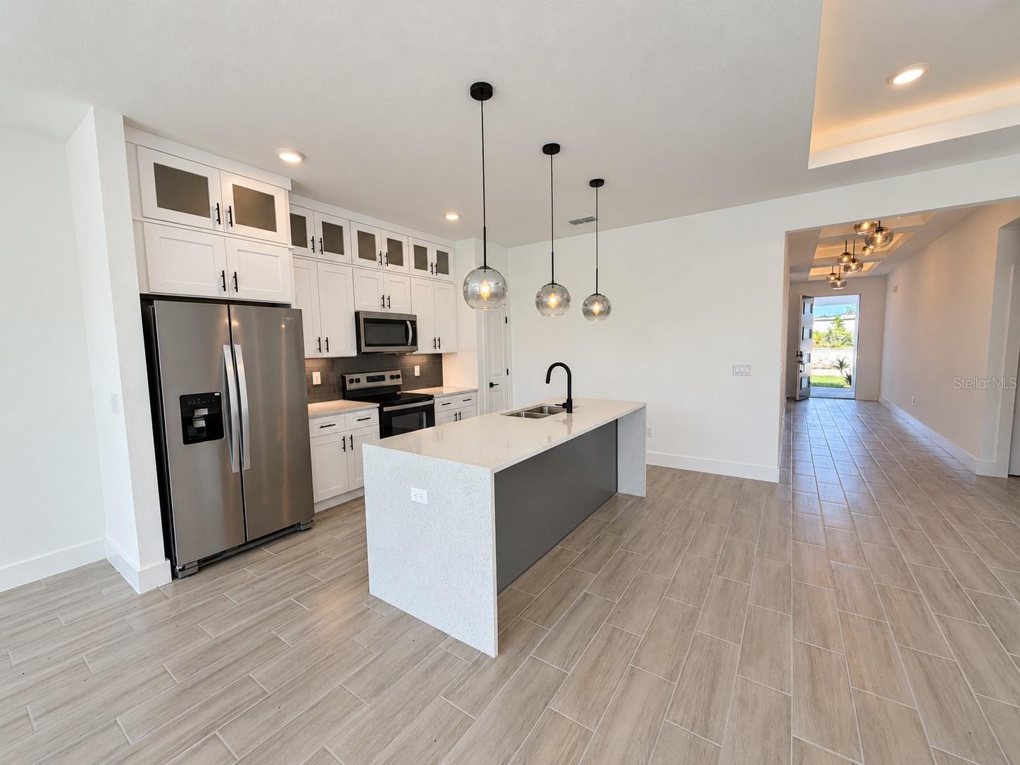 Kitchen toward entry. Actual property photo, digitally refined.