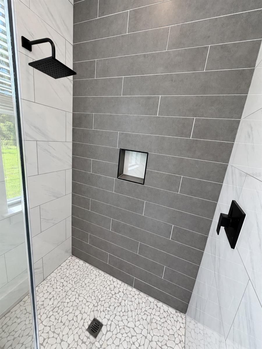 Primary shower tile detail. Actual property photo, digitally refined.