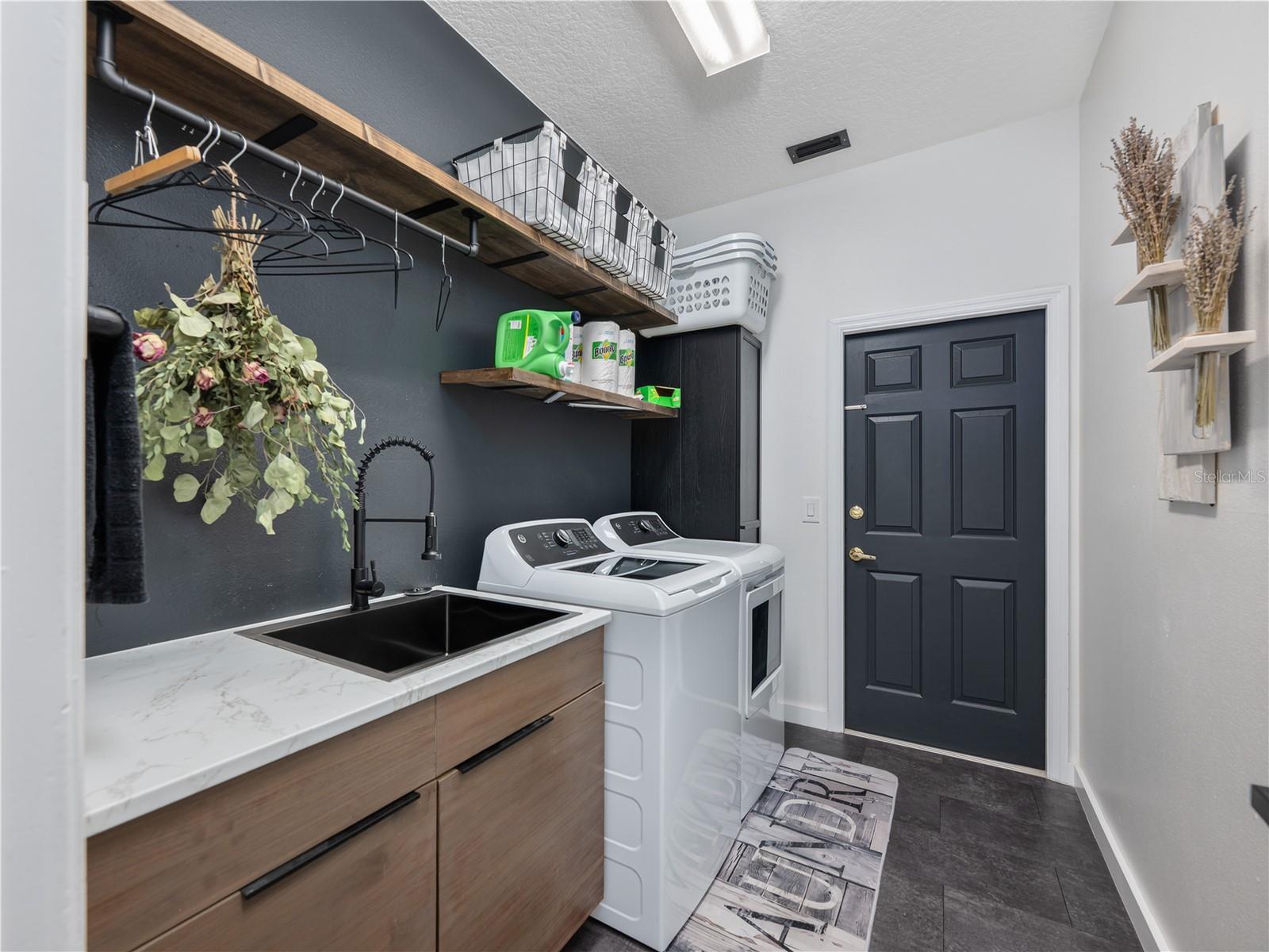 Beautiful laundry room featuring built-in shelving and a functional utility sink.