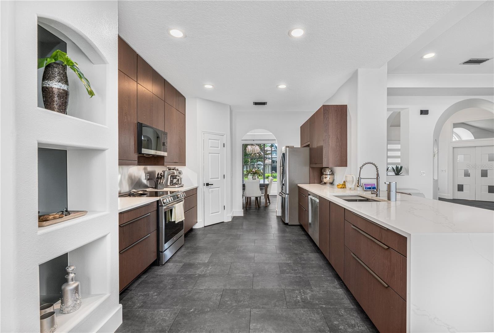 Modern kitchen featuring beautiful cabinetry, waterfall quartz counters, and stainless steel appliances.