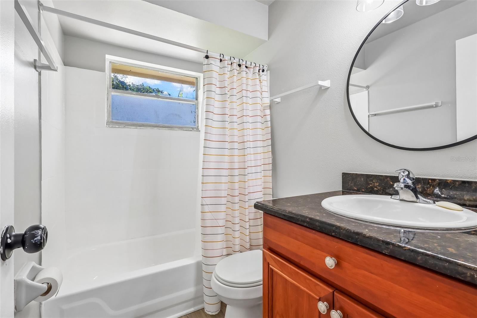 The guest bathroom features a tub/shower combo, updated vanity, and a decorative mirror