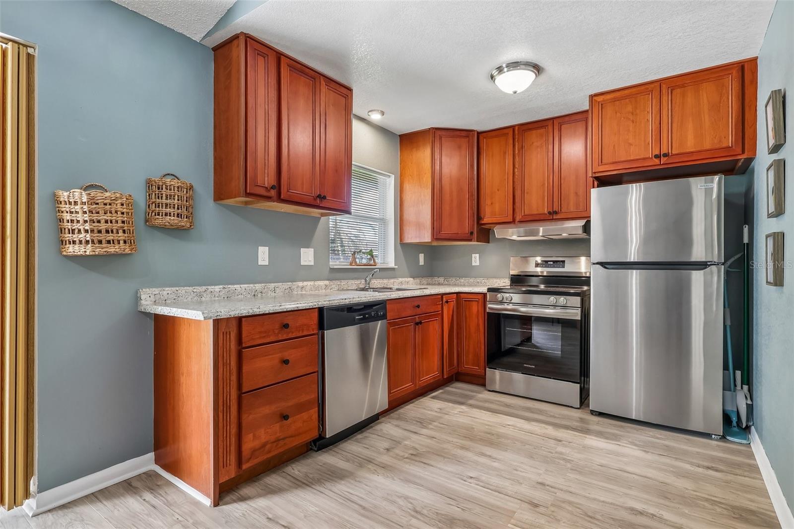 Beautiful updated kitchen! The reddish wood cabinets offer a warmth to the home and there are stainless steel appliances for a sleek look